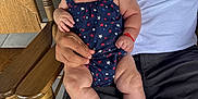 Evelyn joined the competition — help win amazing prizes! baby, infant, child, person, sitting, rocking_chair, wooden_chair, adult_hand, romper, red_shoes, star_pattern, casual_clothing, smiling, indoors, portrait, cute, hair_bow, caucasian_skin, relaxed, family