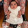 baby, child, car_seat, white_dress, headband, shoes, floral_pattern, indoors, wooden_floor, cute, infant, portrait, seated, looking_at_camera, female, soft_lighting, expression, hands, feet, comfortable