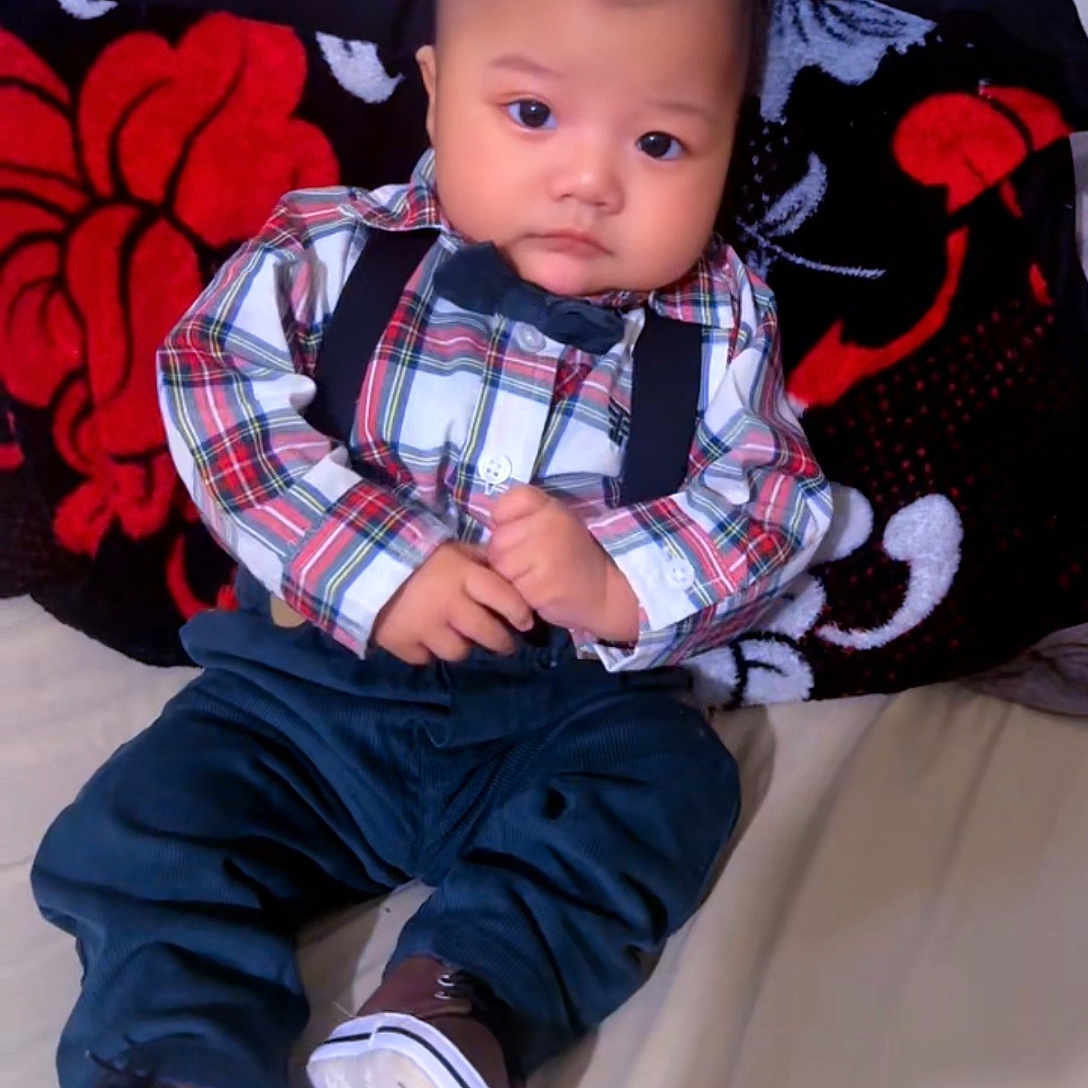Eiden Ochoa joined the competition — help win amazing prizes! baby, bed, blanket, bow_tie, child, clothing, cute, floral_pattern, footwear, indoor, infant, pants, person, plaid_shirt, portrait, serious_expression, shoes, sitting, suspenders, young_child