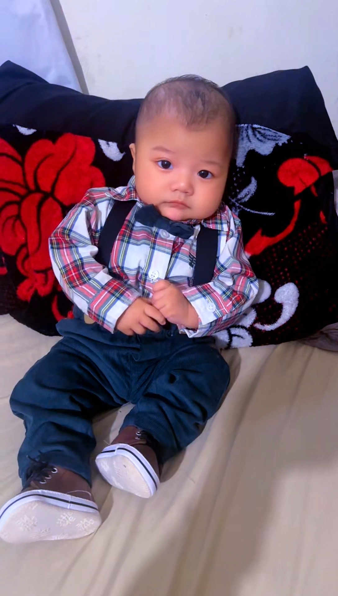 Eiden Ochoa joined the competition — help win amazing prizes! baby, child, plaid_shirt, bow_tie, suspenders, pants, shoes, bed, blanket, floral_pattern, indoor, cute, serious_expression, portrait, sitting, young_child, infant, person, clothing, footwear
