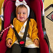 Layal participe au concours pour gagner de l'argent avec cette photo : baby, car_seat, child, smiling, headband, jacket, white_clothing, black_strap, pink_pacifier_clip, footwear, indoor, floor, toy, happy, person, infant, seatbelt, toddler, cute, sitting