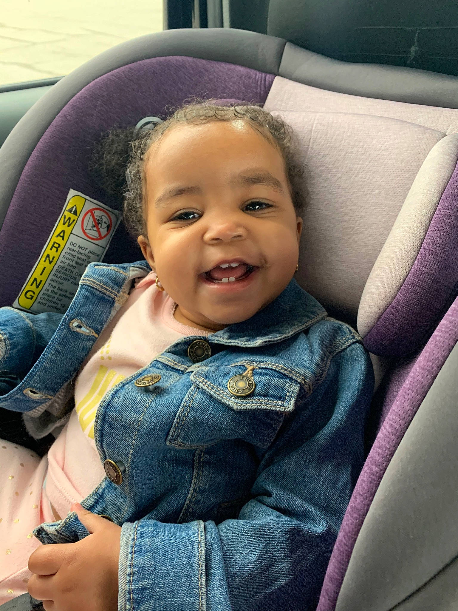 Erykah is registered to the contest to win money with this photo: auto_part, baby, baby_in_car_seat, car, car_seat, cheek, child, face, finger, fun, hand, head, jeans, mouth, person, seat_belt, sitting, skin, smile, toddler