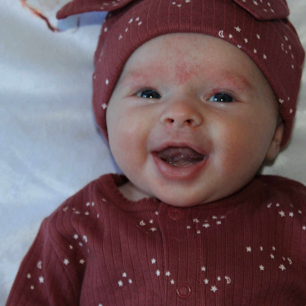 Ella is registered to the contest to win money with this photo: baby, beanie, bodypart, bonnet, cap, clothing, face, happy, hat, head, hood, hoodie, knitwear, newborn, person, photography, portrait, smile, sweater, sweatshirt