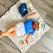 Lylio participe au concours pour gagner de l'argent avec cette photo : baby, child, smiling, blue_clothing, white_clothing, hat, donald_duck, plush_toy, floor, wood_floor, mat, textile, infant, cute, portrait, sitting, happy, indoor, person, toy