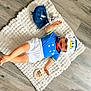 baby, child, smiling, blue_clothing, white_clothing, hat, donald_duck, plush_toy, floor, wood_floor, mat, textile, infant, cute, portrait, sitting, happy, indoor, person, toy