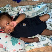 Amari is registered to the contest to win money with this photo: baby, infant, blanket, pillow, onesie, socks, lying_down, indoor, child, cute, patterned, raising_arm, soft_lighting, portrait, resting, colorful, cozy, bed, sleepwear, newborn