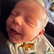 Dante joined the competition — help win amazing prizes! baby, newborn, infant, sleeping, smiling, closeup, face, skin, nose, mouth, ear, onesie, animal_print, fabric, portrait, couch, cozy, happy, peaceful, tiny_person