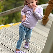 Harper is registered to the contest to win money with this photo: child, toddler, girl, pose, purple_shoes, crocs, jeans, long_sleeve, pink_top, wooden_deck, railing, outdoor, portrait, cute, playful, smile, casual_clothing, blurred_background, shallow_depth_of_field, person