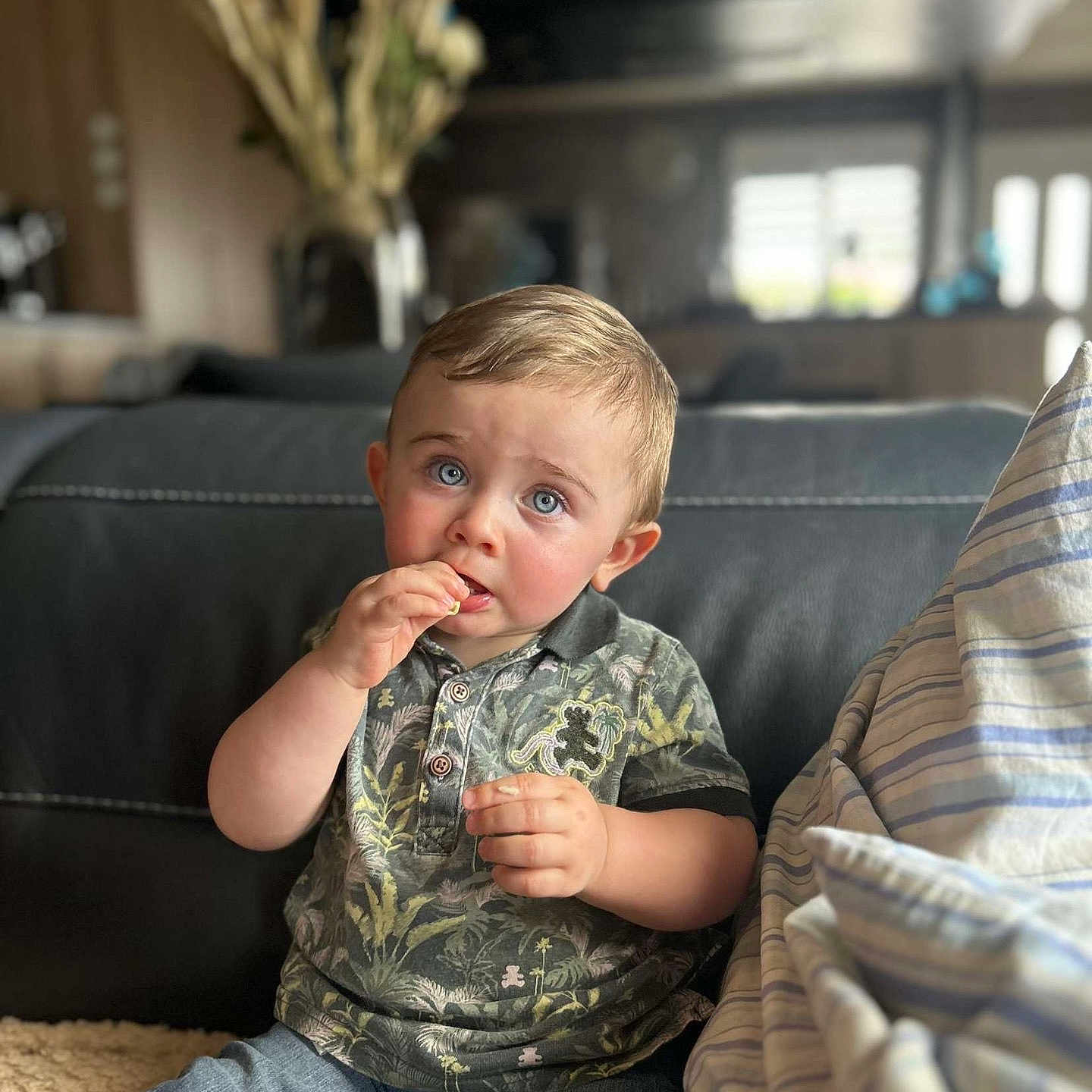 Mélio participe au concours pour gagner de l'argent avec cette photo : blue_eyes, casual_clothing, child, couch, curious, cushion, expression, face, furniture, home, indoor, jeans, person, polo_shirt, portrait, sitting, snack, soft_lighting, toddler, young_child