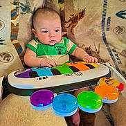 Atticus joined the competition — help win amazing prizes! baby, child, toy, piano, colorful, music, infant, onesie, blanket, animal_print, hands, feet, indoor, cute, focused, play, seat, soft, bright, learning