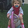 child, toddler, playground, rocker, pacifier, curly_hair, pink_sneakers, red_vest, striped_shirt, outdoor, stroller, adult, grass, toy, play, person, casual_clothing, feet, fence, smiling