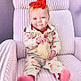 baby, child, red_bow, headband, heart_pattern, plush_chair, knitted_toy, pink_socks, smile, cute, indoors, cozy, clothing, person, infant, portrait, seated, happy, soft_texture, playful