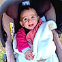 baby, blue_eyes, blanket, car_seat, child, clothing, cozy, cute, expression, face, hand, infant, joyful, outdoor, person, pink_clothing, portrait, smile, white_blanket, wrapped