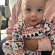 Leon a rejoint le concours — aidez-le/la à gagner de superbes lots ! adult_hand, baby, child, christmas_trees, cozy, cute, eyes, face, family, holding, holiday_clothing, indoor, infant, pajamas, patterned_clothing, person, pink_hoodie, reindeer, smile, warm
