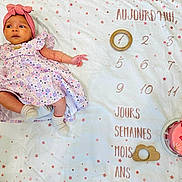 Eline participe au concours pour gagner de l'argent avec cette photo : baby, infant, girl, dress, headband, blanket, milestone, cake, celebration, pink, stars, wooden_ring, milestone_blanket, one_month, lying_down, cute, newborn, portrait, celebratory_cake, child