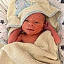 newborn, baby, towel, blanket, star_pattern, hooded_towel, infant, skin, face, hands, lying_down, cute, soft_texture, wrapped, bed, resting, indoors, peaceful, closeup, portrait