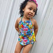 Harmony is registered to the contest to win money with this photo: child, toddler, swimsuit, colorful_clothing, pink_bow, curly_hair, smiling, outdoor, white_wall, standing, portrait, playful, young_girl, summer, casual, fashion, cute, happy, person, nature