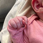 Milana is registered to the contest to win money with this photo: baby, hand, fist, pink_clothing, ear, skin, infant, closeup, sleeve, fabric, blanket, soft, newborn, tiny, folded_hand, baby_garment, human, child, indoors, portrait