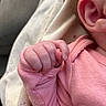 baby, hand, fist, pink_clothing, ear, skin, infant, closeup, sleeve, fabric, blanket, soft, newborn, tiny, folded_hand, baby_garment, human, child, indoors, portrait