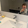 child, toddler, bathroom, sink, mirror, toothbrush, brushing_teeth, pacifier, sponge, water_faucet, bathtub, tiles, window, reflection, white, clean, plumbing, person, interior, hygiene