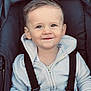 toddler, child, face, smile, hoodie, car_seat, straps, beads, name_tag, person, baby, clothing, cute, happy, young_child, seatbelt, portrait, indoor, hand, light