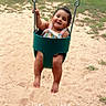 toddler, child, swing, playground, sand, grass, smile, happy, outdoor, summer, yellow_chain, green_swing, footprints, tree, house, person, casual_clothing, baby, play, fun