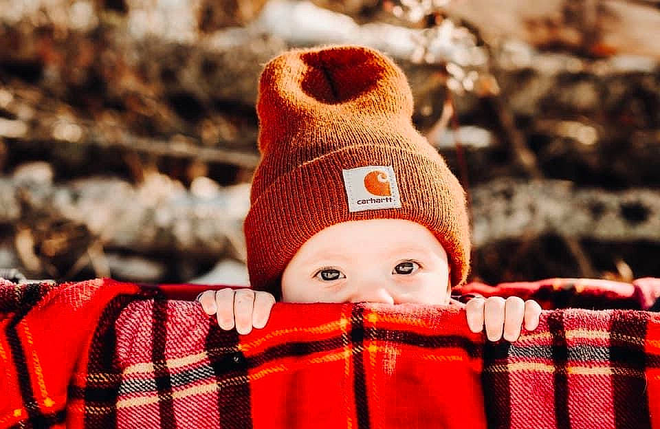 Zeplyn is registered to the contest to win money with this photo: baby_toddler_clothing, cap, carmine, close_up, costume_hat, eye, fashion_accessory, fur, happy, knit_cap, pattern, person, plaid, red, sleeve, tartan, textile, winter, wood, wool