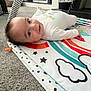 baby, infant, playmat, carpet, smiling, indoor, toy, colorful, rainbow, stars, white_clothing, floor, child, happy, person, head, face, crawling, play, home