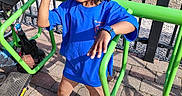 Jaheim is registered to the contest to win money with this photo: child, smiling, peace_sign, bucket_hat, blue_shirt, watch, green_bike_rack, pavement, railroad_tracks, metal_fence, outdoor, sunny, person, casual_clothing, shoes, curly_hair, happy, standing, urban, daytime