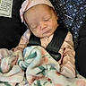 baby, blanket, car_seat, child, closeup, cute, face, floral_pattern, headband, indoors, infant, newborn, peaceful, pink_clothing, portrait, resting, safety_harness, sleeping, soft_texture, toddler