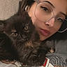 Stella is registered to the contest to win money with this photo: woman, cat, kitten, glasses, piercing, face, pet, cute, indoor, portrait, casual_clothing, closeup, snuggling, animal, feline, young_adult, relaxed, soft_lighting, eyewear, home