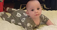 Calvin is registered to the contest to win money with this photo: baby, infant, onesie, bear_pattern, blanket, lying_down, indoors, child, face, cute, soft_lighting, carpet, floor, person, toddler, expression, sleepwear, young_child, home, portrait