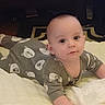 baby, infant, onesie, bear_pattern, blanket, lying_down, indoors, child, face, cute, soft_lighting, carpet, floor, person, toddler, expression, sleepwear, young_child, home, portrait