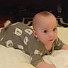 Calvin is registered to the contest to win money with this photo: baby, infant, child, lying_down, clothing, bear_pattern, soft_surface, indoors, curious, face, head, person, cute, young, pajamas, blanket, toddler, sleepwear, expression, carpet