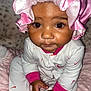 baby, infant, child, pink_bonnet, onesie, colorful, blanket, soft_texture, cute, curious, indoor, portrait, closeup, hands, face, eyes, sitting, clothing, adorable, young_child