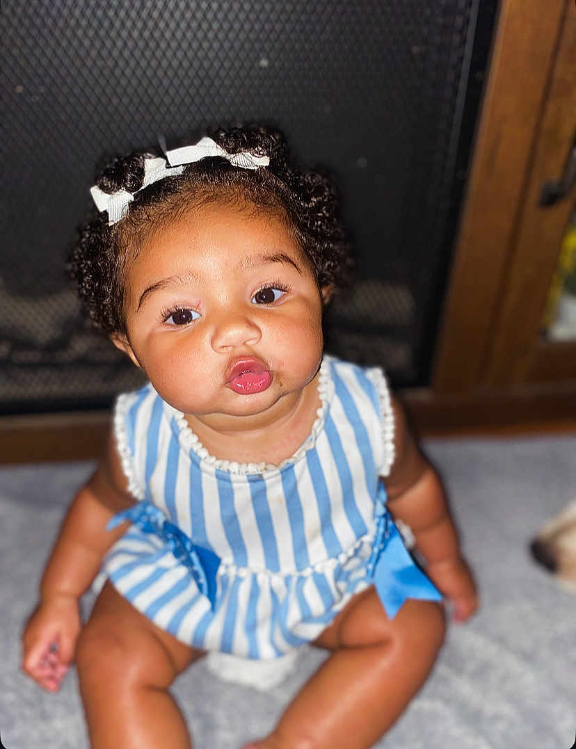 Elina joined the competition — help win amazing prizes! baby, child, curly_hair, bow, blue_striped_dress, sitting, carpet, indoor, fireplace_screen, cute, pout, infant, adorable, skin, face, person, young, expression, chubby_cheeks, portrait
