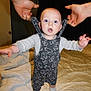 baby, child, overalls, patterned_clothing, bed, blanket, hands, indoor, person, infant, standing, white_socks, blue_eyes, expression, cute, support, bedroom, door, curtains, sleepwear