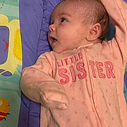 Maribel is registered to the contest to win money with this photo: baby, infant, child, pink_onesie, sleepwear, face, head, lying_down, colorful_mat, patterned_mat, curious_expression, small_hands, newborn, padded_surface, looking_sideways, soft_fabric, cute, young_child, indoors, portrait