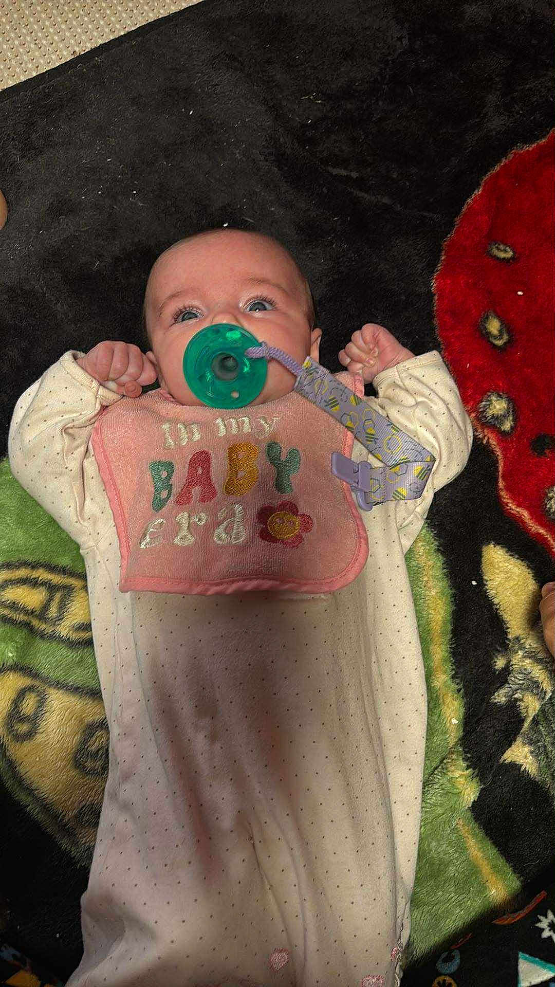 Maribel joined the competition — help win amazing prizes! baby, infant, pacifier, bib, onesie, blanket, polka_dots, lying_down, clothing, child, cute, face, hand, patterned, colorful, fabric, soft, indoor, young, newborn