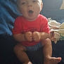 Kason is registered to the contest to win money with this photo: baby, blanket, blue_shorts, casual, child, comfortable, couch, expression, face, feet, furniture, hands, home, indoor, infant, person, red_shirt, sitting, soft_lighting, young
