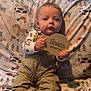 Kason is registered to the contest to win money with this photo: animal_print, baby, blanket, child, clothing, curious, cute, fabric, face, hands, indoor, infant, overalls, person, portrait, seated, socks, soft_lighting, window, wooden_sign