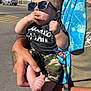 adult, baby, blue_towel, camouflage, casual, child, clothing, foot, hand, holding, outdoor, pacifier, parking_lot, person, shopping_cart, street, sunglasses, sunny_day, tattoo, walmart