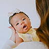 Nevaeh joined the competition — help win amazing prizes! baby, infant, child, face, headband, bow, yellow_dress, person, hand, long_hair, skin, cute, portrait, expression, looking, holding, gentle, soft_light, indoor, closeup