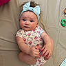 baby, infant, child, headband, blue_bow, hello_kitty, onesie, cute, skin, hands, feet, toy, blanket, pattern, fabric, lying_down, curious, indoor, playful, cozy