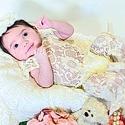 Love is registered to the contest to win money with this photo: baby, child, closeup, curious, cute, decorative, flowers, headband, indoors, infant, lace_clothing, pillow, pink_flower, portrait, resting, smile, soft_texture, soft_toy, teddy_bear, white