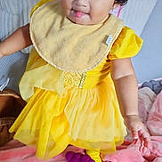 Merida is registered to the contest to win money with this photo: baby, bedroom, bib, child, curly_hair, cute, expression, fabric, face, feet, hand, indoor, pink_blanket, playful, playpen, plush, smiling, soft_toys, toddler, yellow_dress