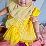 baby, bedroom, bib, child, curly_hair, cute, expression, fabric, face, feet, hand, indoor, pink_blanket, playful, playpen, plush, smiling, soft_toys, toddler, yellow_dress