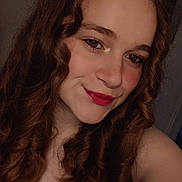 Julie participe au concours pour gagner de l'argent avec cette photo : person, female, curly_hair, smile, tank_top, indoor, portrait, young_person, brown_hair, makeup, lipstick, casual_clothing, face, eyebrows, skin, shoulder, selfie, light, expression, cartoon_character