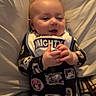 Forrestt joined the competition — help win amazing prizes! baby, infant, smiling, onesie, bib, pillow, bed, cozy, portrait, happy, child, clothing, hands, cute, soft, indoor, sleepwear, face, person, lying_down