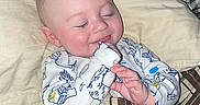Forrestt is registered to the contest to win money with this photo: baby, child, sleeping, smiling, pajamas, blanket, bed, pillow, cozy, face, infant, cute, indoor, resting, comfort, patterned, plaid, hands, peaceful, soft_light